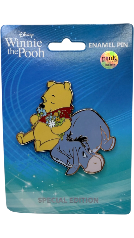 Graidan Collectibles Winnie the Pooh and Eeyore enamel pin featuring Pooh holding flowers on a blue display card